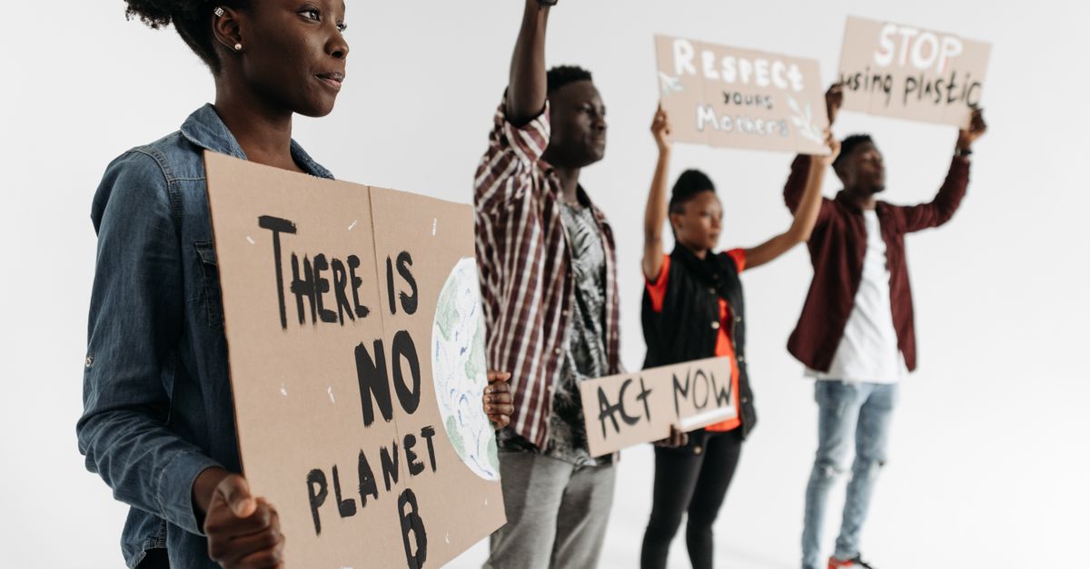 Diverse group holding protest signs advocating for climate action with phrases like 'There is No Planet B'.
